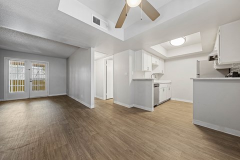 an empty living room and kitchen with a ceiling fan